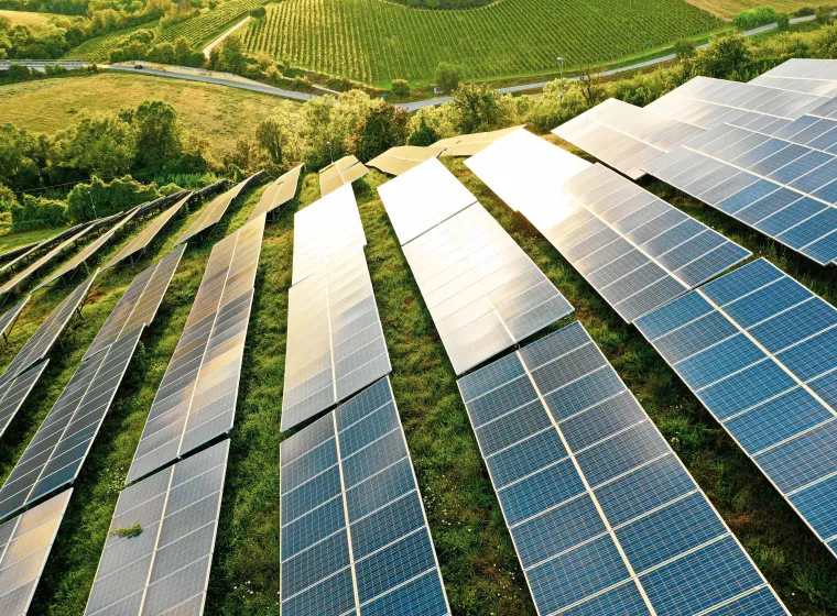 Multiple solar panels placed throughout a grassy field on a hill