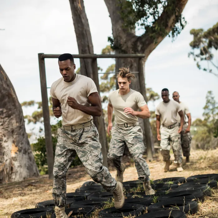 Young military soldiers practicing tyre obstacle course at boot camp